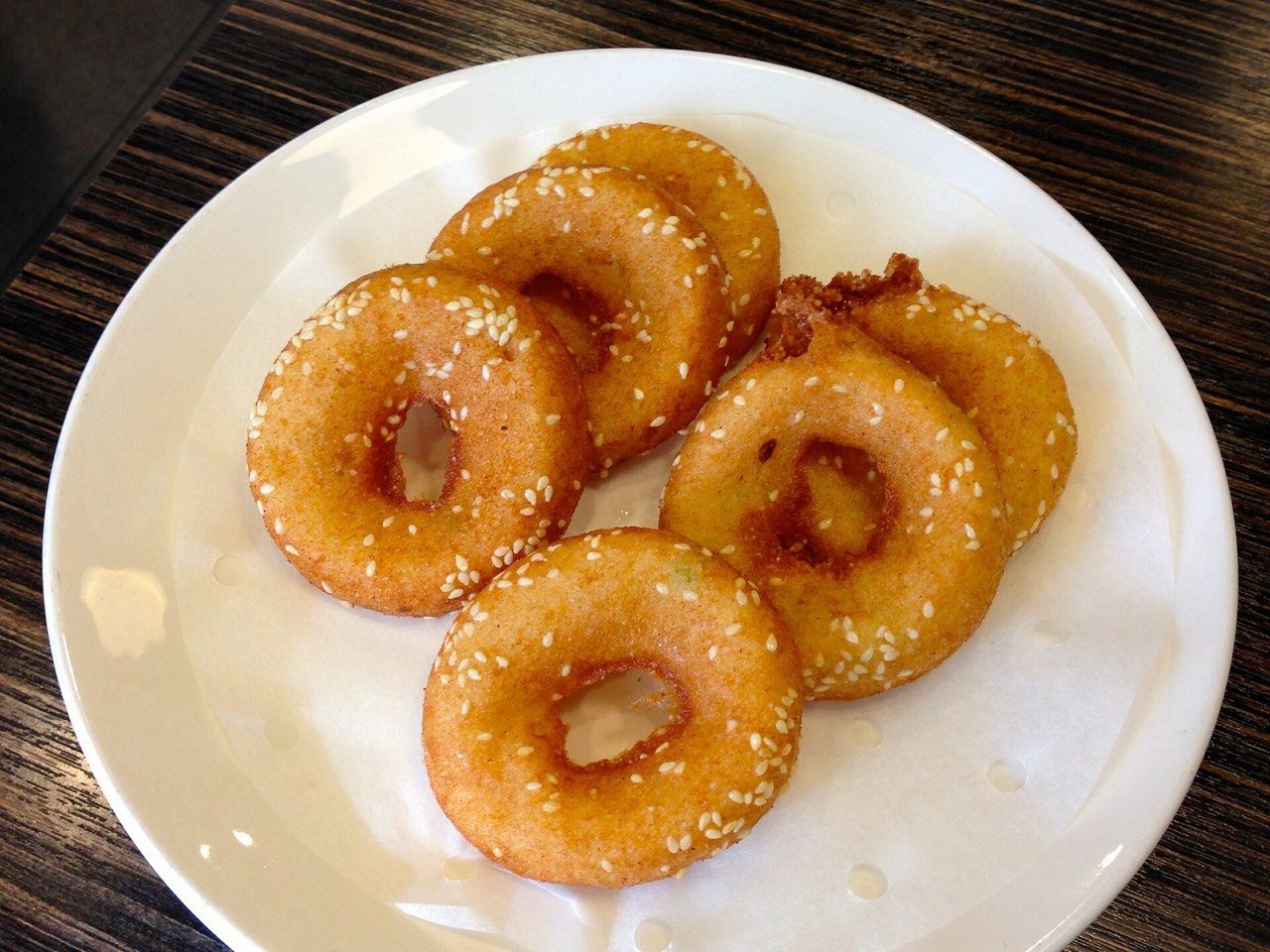 Freshly fried mian wo — golden ring-shaped rice fritters covered in sesame seeds